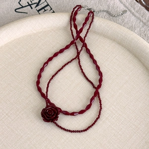 Detailed macro view of vintage layered deep red rose bead necklace with silver chain extender