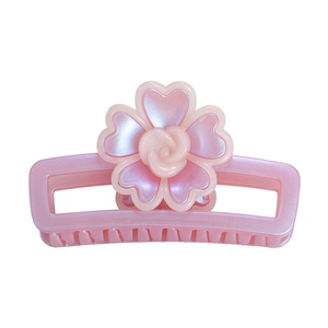 Détail d'une pince à cheveux rose en forme de fleur avec pétales en cœur et bouton