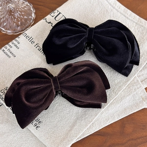 Close-up of velvet bow banana clips in black and dark brown with soft fabric texture