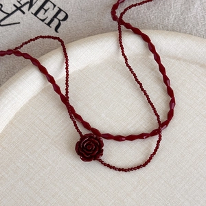Detailed macro view of vintage red rose pendant and layered beaded choker chain