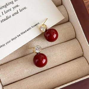 Gros plan de boucles d'oreilles en perles rouges et zircons dans une boîte en bois