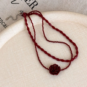 Detailed macro view of vintage red double-layered beaded necklace with rose flower pendant