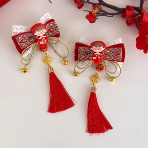 Détail de barrettes Nouvel An rouge avec nœuds en velours, glands et cloches dorées