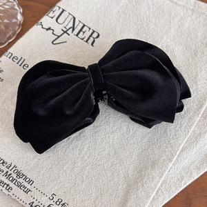 Detail of layered black velvet bow hair clip on elegant linen background fabric