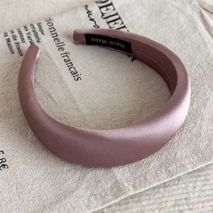 Detail eines handgefertigten lila Satin-Haarreifs mit hohem Profil und Markenetikett