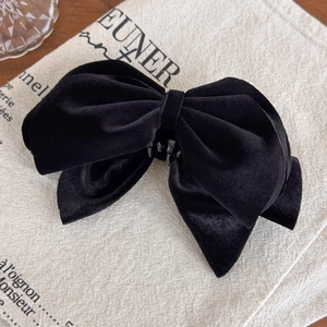 Close-up of the large black velvet bow hair clip showing soft matte fabric texture