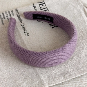 Detailansicht eines lila gestrickten Haarreifs mit hohem Design und handgemachtem Etikett