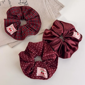 Three-piece red vintage scrunchie set with cherry labels in plaid, satin, and polka dot patterns