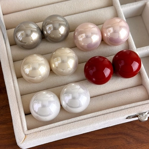 Detailed view of five multi-colored 25mm baroque pearl stud earrings in a beige jewelry box