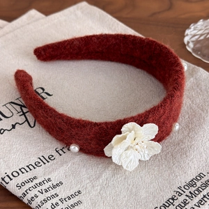 Macro detail of wine red knitted headband with white camellia flower and pearls