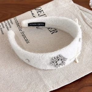Detail of white plush snowflake headband with rhinestones and handmade label