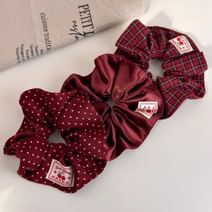 Three vintage hair scrunchies featuring red polka dots, solid satin, and classic plaid patterns