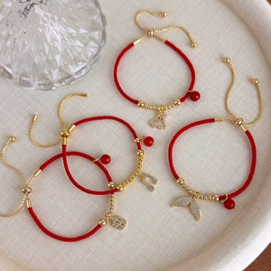 Bracciale a cordino rosso intrecciato regolabile con ciondoli dorati tra cui coda di pesce e nota