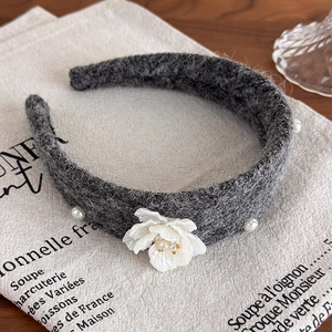 Detailed shot of dark grey wool headband featuring white camellia flower and pearl accents