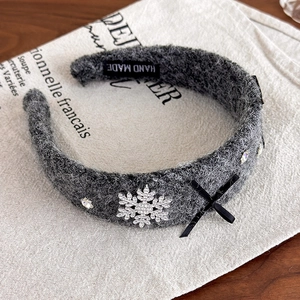 Detailed macro view of rhinestone snowflake and black bow on grey plush headband