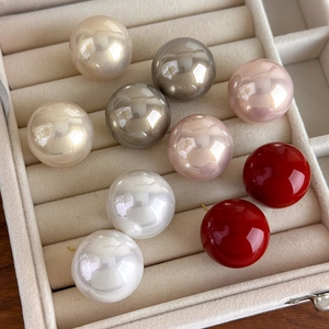 Close-up of 25mm large pearl stud earrings in five colors on beige velvet display