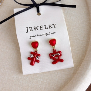 Détail de boucles d'oreilles cœur rouges festives avec caractères porte-bonheur dorés