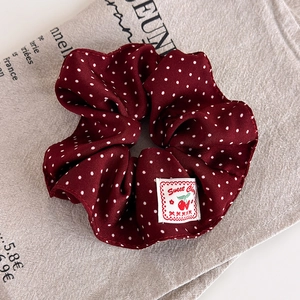 Close-up of vintage red polka dot scrunchie featuring a sweet cherry fabric label