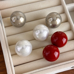 Detail of 25mm baroque pearl earrings in white, metallic gray and red on velvet display