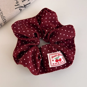 Detailed shot of dark red polka dot scrunchie with Sweet Cherry woven label detail