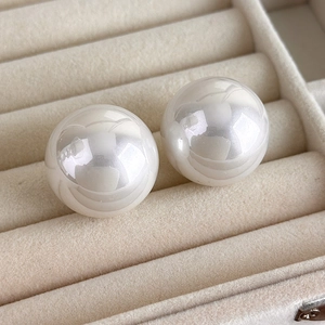 Detailed close-up of 25mm large Baroque pearl earrings on a soft velvet jewelry tray