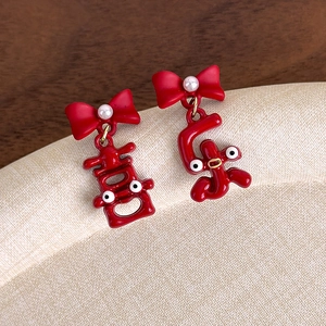 Détail de boucles d'oreilles festives rouges avec nœud, perle et caractères Xi et Le