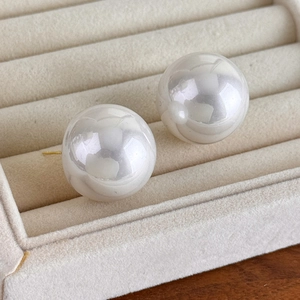 Close-up of 25mm white baroque pearl earrings on beige velvet jewelry display