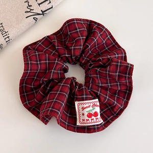 Detail of red and navy plaid scrunchie with Sweet Cherry woven label and cotton texture