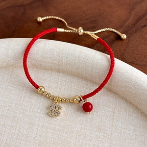 Dettaglio del bracciale rosso intrecciato con ciondolo a segno di dollaro scintillante
