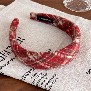 Detailed macro view of the handmade red plaid wide fabric headband with a woven label