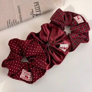 Three-piece retro burgundy scrunchie set with polka dot, satin, and plaid fabric textures