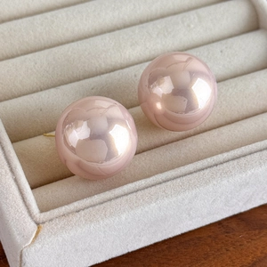 Close-up of 25mm baroque pink pearl stud earrings in a beige velvet jewelry box tray