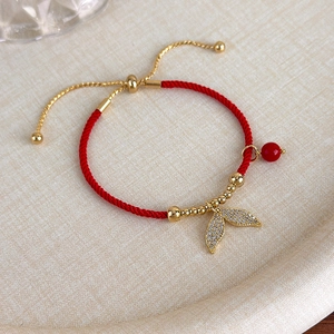 Dettaglio del bracciale intrecciato rosso con ciondolo a coda di pesce e zirconi