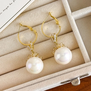 Close-up of elegant red pearl drop earrings with gold hooks on a beige velvet display box