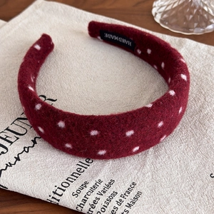 Detail of burgundy polka dot padded headband with handmade label on linen background