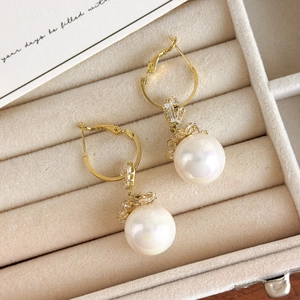 Detailed macro view of long pearl drop earrings on a premium beige velvet jewelry box