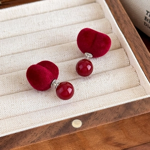 Orecchini a sfera in velluto bordeaux vintage esposti in una scatola portagioie in legno