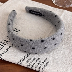 Detail of gray plush polka dot headband featuring a white Handmade label on the inner lining