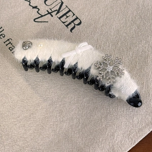 Détail de la pince à cheveux banane en fausse fourrure blanche avec flocon et nœud en satin