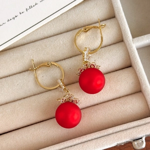 Detail of red matte pearl earrings with gold floral base and zircon inlay on velvet box