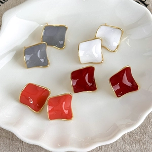 Detailed view of four colorful geometric square earrings in a shell-shaped ceramic tray