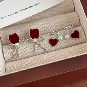 Detail of red flocked tulip and heart cherry earrings with pearls in a beige jewelry box