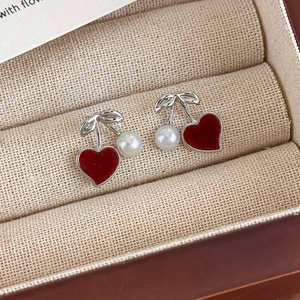 Macro shot of cherry-shaped earrings with red flocked hearts and white pearls