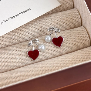 Close-up of cherry-style earrings with red velvet hearts and pearls in a jewelry box