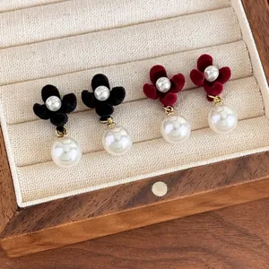 Elegant velvet flower earrings with pearls in black and wine red on a display tray