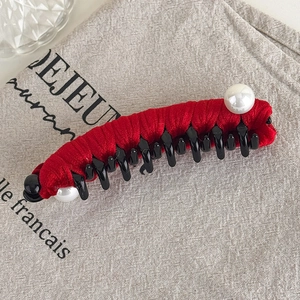 Detail of red velvet banana clip hair claw with pearl accents on grey linen surface