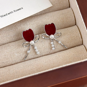 Detail of red flocked tulip earrings with silver bows and hanging pearl drop tassels