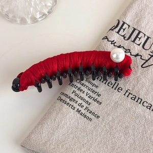 Macro detail of vintage red velvet banana hair clip with elegant large pearl embellishment