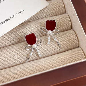 Close-up of red tulip bow earrings with velvet texture and pearls in a jewelry box