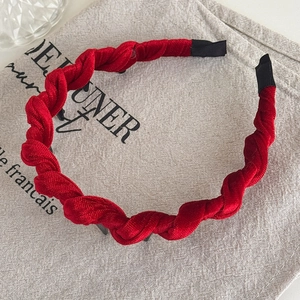 Detail of red twisted velvet headband with textured fabric on a gray linen background
